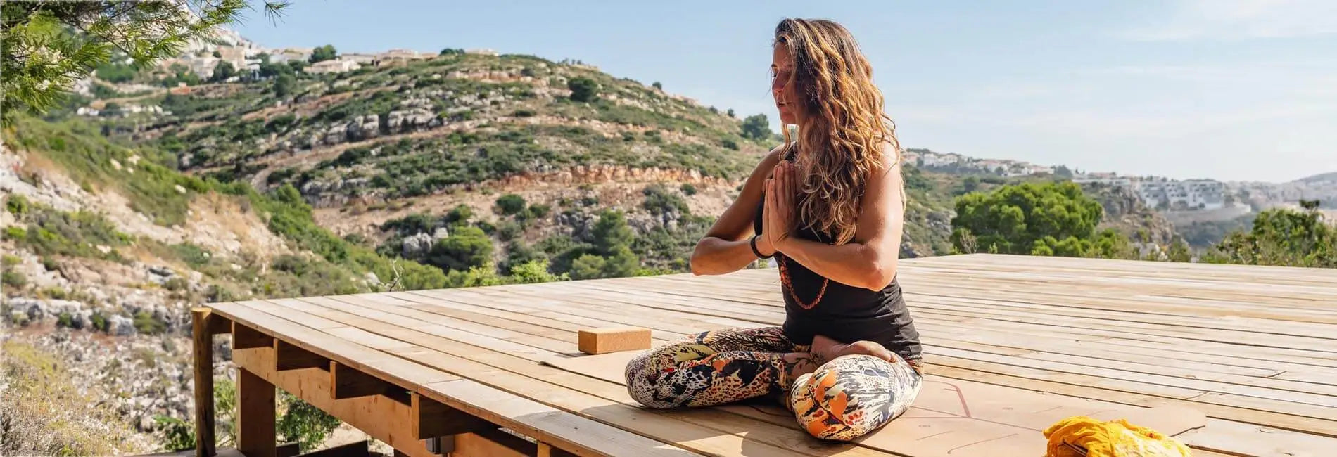 Collection vêtements yoga femme, yogini sur une terrasse en bois faisant la posture Namasté | Achamana