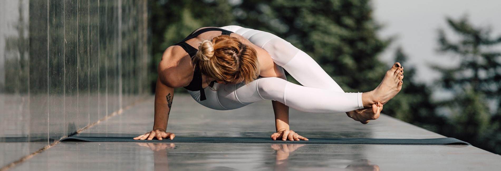Collection vêtement yoga dynamique - Yogini réalisant la posture de la pince sur une terrasse | Achamana