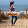 Legging yoga bio - yogini portant un legging de yoga noir un haut lavande et un sac de yoga en liège au bord de la plage | Achamana